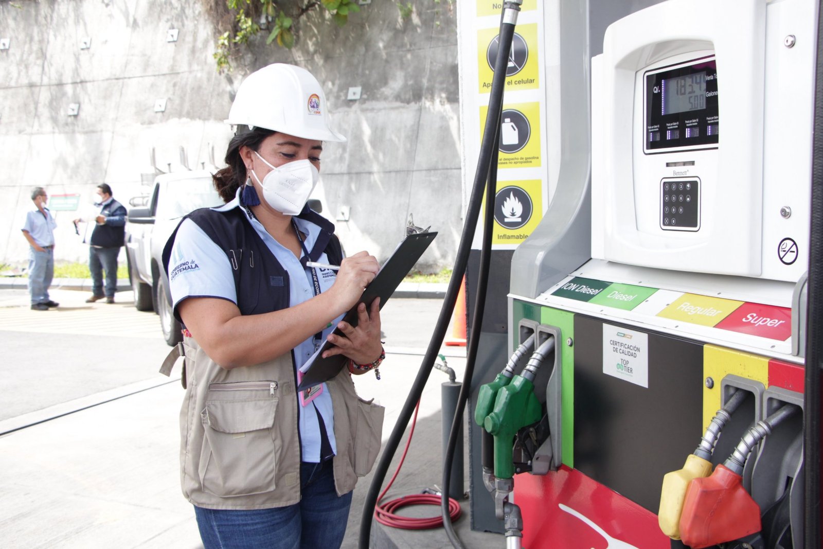 Inspectora de la DIACO revisando precios en surtidor de combustible.